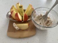 Sliced apple on cutting board with cinnamon dip at side
